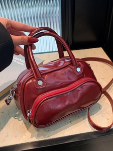 Bordeaux red glossy crossbody bag with dual zipper design and adjustable shoulder strap