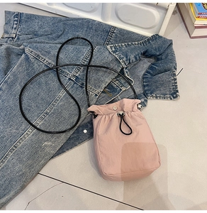 Detail of light pink drawstring mini bucket bag with silver metal snap and nylon fabric
