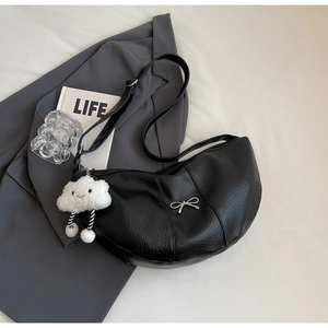 Detail of black pebbled PU leather crescent bag with silver bow and cloud plush charm
