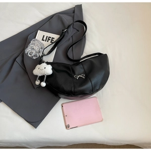 Detail of black pebbled leather crescent bag with silver bow and white plush cloud charm