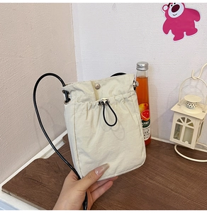 Detail view of cream canvas phone bag featuring a secure drawstring and magnetic closure