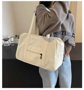 Détail d'un grand sac de voyage en toile beige avec poignées renforcées dans un café