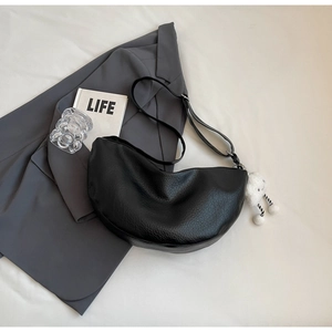 Black lychee leather crescent bag with cloud pendant shown in a flat lay setup