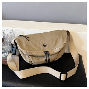 Close-up of khaki nylon saddle bag with black circular logo on black leather surface
