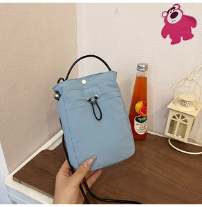 Detail of light blue fabric crossbody phone bag with drawstring and snap button closure