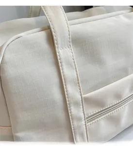 Gros plan sur le tissu en nylon crème texturé et la poche extérieure du sac de voyage