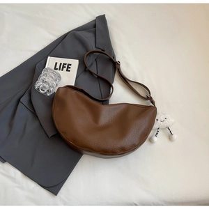 Brown litchi grain crescent bag displayed on a grey blazer for a chic casual style