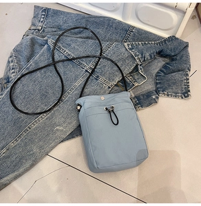 Detail of light blue canvas phone bag with drawstring closure and front pocket