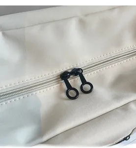 Détail de deux fermetures éclair circulaires noires sur tissu ripstop beige du sac de voyage