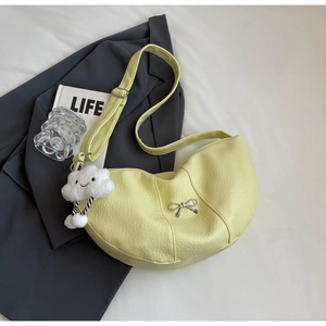 Detail of light yellow crescent hobo bag with silver bow and plush cloud charm