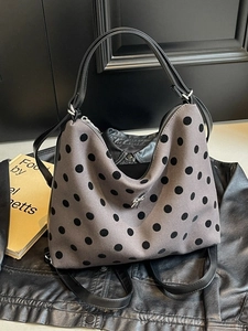 Polka dot canvas tote bag with metal bow detail displayed on a black leather jacket