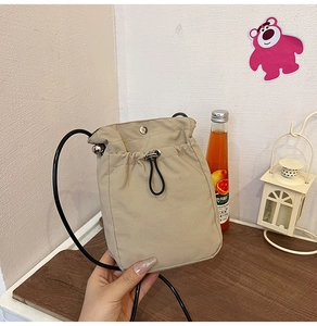 Detail of light beige crossbody phone bag with drawstring closure and magnetic buckle