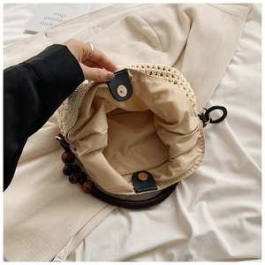 Detail of hollow knit tote featuring round wooden bead handles and secure magnetic closure