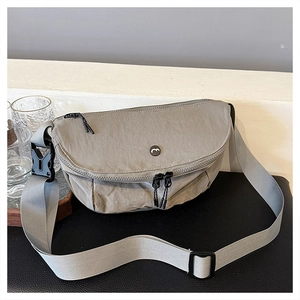 Close-up of light grey nylon saddle bag with circular M logo and black double zippers