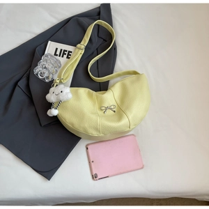 Detail of yellow crescent crossbody bag with silver bow buckle and cloud plush pendant