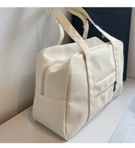 Gros plan d'un sac de voyage crème montrant la poche zippée et la texture du tissu