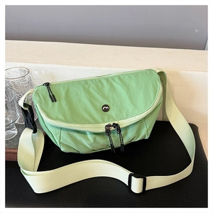 Detail view of mint green nylon crossbody bag with wide strap and zip on black leather