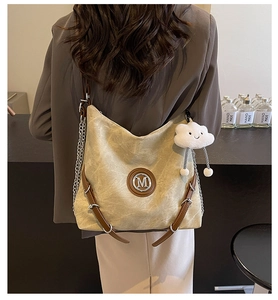 Detail of beige tote bag with grain texture, silver chain strap and M logo charm
