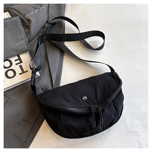 Detail of black sporty crossbody saddle bag with dual zippers and water-resistant texture