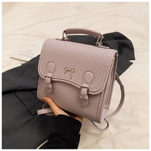 Detail der fliederfarbenen Webstruktur-Tasche mit goldener Schleife und Schnallen