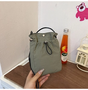 Detail of sage green canvas bucket bag with black drawstring and metal magnetic clasp