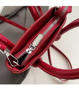 Gros plan sur la fermeture éclair argentée lisse d'un sac à main rouge en cuir huilé