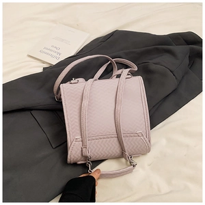 Detail des hellvioletten Rucksacks mit V-Webstruktur auf einer grauen Anzugjacke
