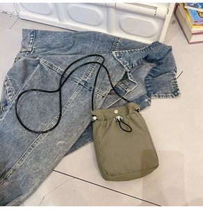 Detail view of army green nylon mini crossbody bag with drawstring closure and strap