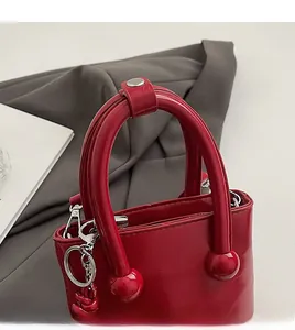 Détail du sac seau en cuir rouge brillant avec poignée boule et fermoirs argentés
