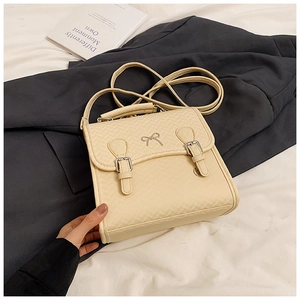 Detailansicht der cremefarbenen Ledertasche mit silberner Schleife und Rautensteppung