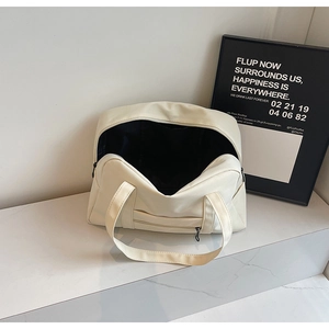 Gros plan du sac de voyage beige avec fermeture éclair et poche avant sur marbre