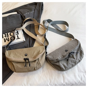 Detail of minimalist washed nylon crescent bags in khaki and grey on fabric background