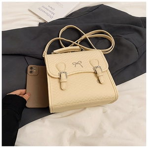 Makroaufnahme einer beigen Stepptasche mit Schleife und Handy als Größenvergleich