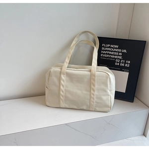 Détail du sac de voyage en toile crème avec poche latérale et bandoulières solides