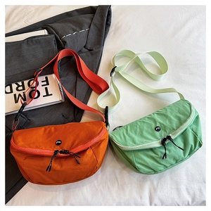 Detail of crescent nylon crossbody bags in orange and green on a stylish background