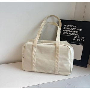 Gros plan du grand sac de voyage en toile crème montrant les sangles renforcées
