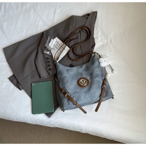 Detail of grey-blue washed leather backpack with brown strap and white plush cloud charm