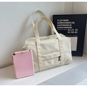 Détail d'un cabas en toile crème montrant une poche zippée avec une tablette rose dedans