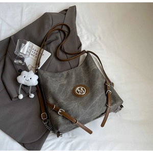 Detail of vintage gray washed tote bag with metal M logo and plush cloud charm