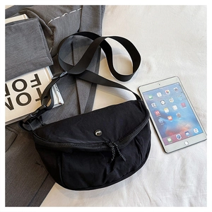 Detailed close-up of a black crescent nylon crossbody bag on a gray minimalist background