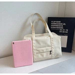 Détail du sac de voyage en toile blanc cassé avec poche zippée et larges poignées