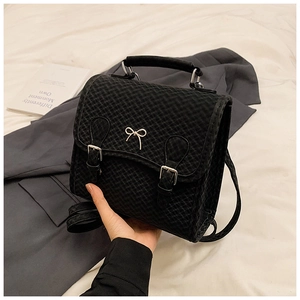 Detail eines schwarzen Rucksacks mit Hahnentritt-Muster und silbernem Schleifenanhänger