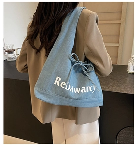 Close-up of denim tote bag with Rebawancy letter print and drawstring side bow detail