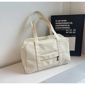 Détail du grand sac de voyage en toile beige avec poche zippée et poignées robustes