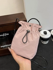 Pink nylon mini crossbody bag with drawstring closure and black round ring handle
