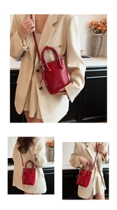 Détail d'un sac seau rouge brillant avec pompons tressés et breloques boules