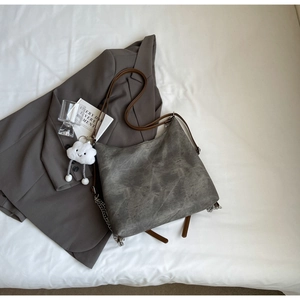 Detailed texture of grey vintage hobo bag with silver chains and cloud plush charm