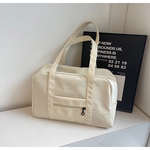 Détail d'un grand sac de voyage blanc cassé avec poche zippée et poignées solides