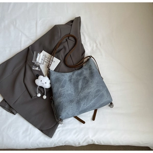 Detail of vintage grey leather tote with brown straps and white cloud charm accessory