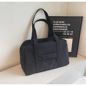 Détail du sac de voyage noir montrant la texture en nylon et la poche avant zippée
